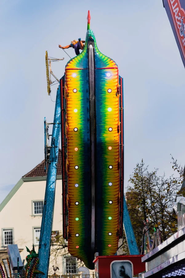 Bunte hohe Fahrgeschäft-Säulen vor einem hellen Himmel