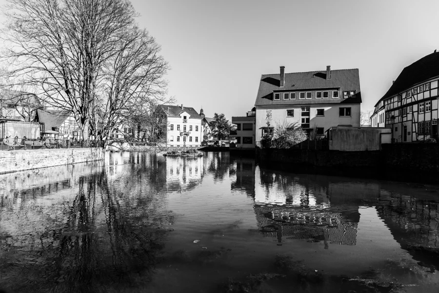 Schwarzweiße Häuser und ein Turm spiegeln sich in einer Wasserfläche