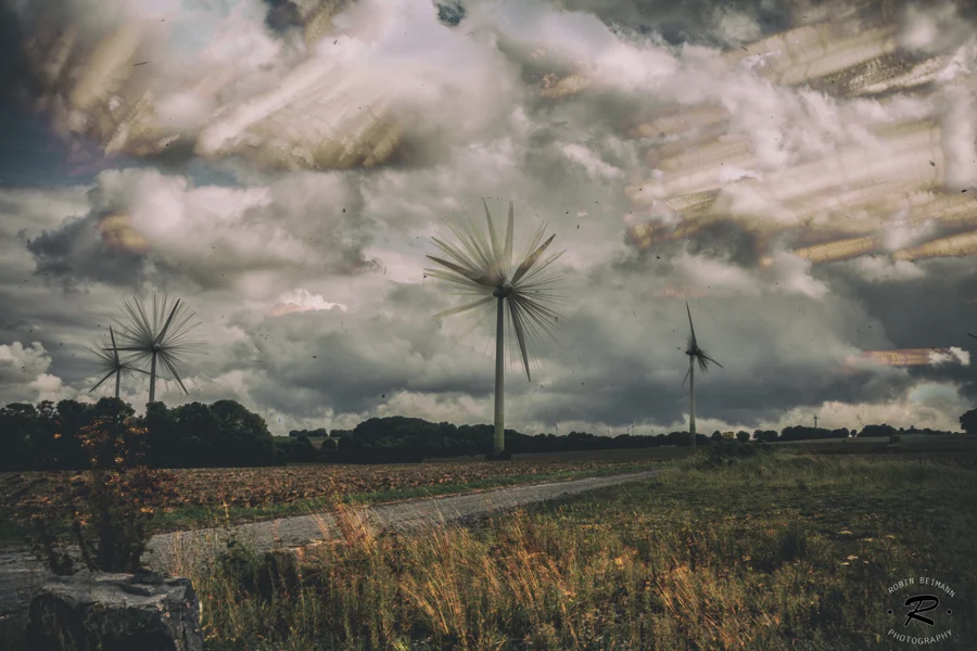 Windräder über Feldern unter einem dramatischen Wolkenhimmel