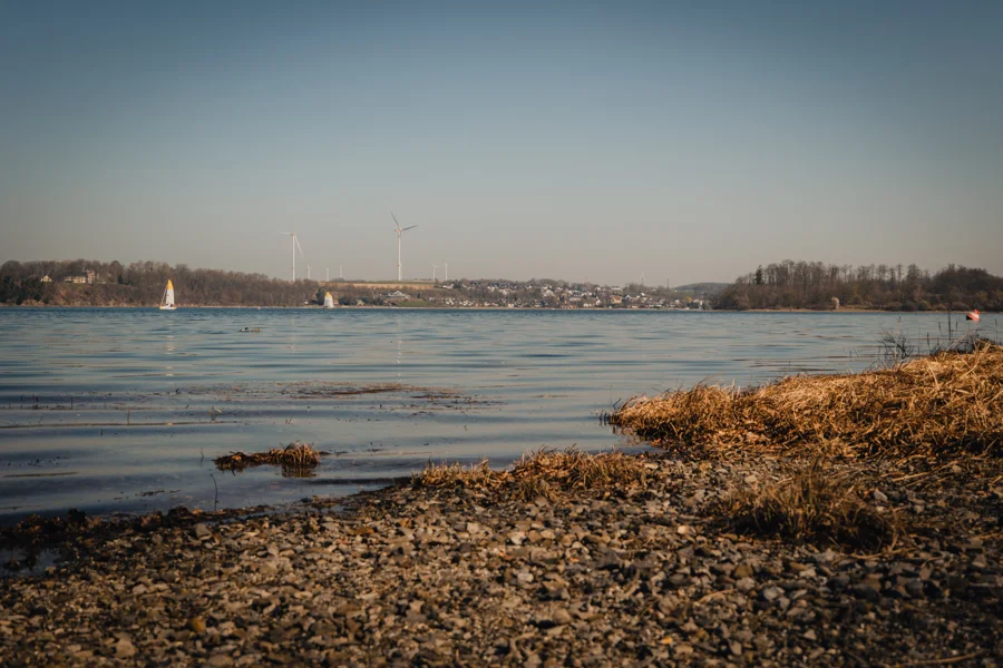 Wasserfläche mit Ufer und weitem Himmel